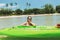 Woman with sunglass sitting in the sea with green kayak on summer vacation.
