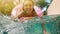 Woman with sunglasses in blue bikini lying in inflatable pink donut float in pool on sunny summer day. Look at camera