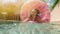 Woman with sunglasses in blue bikini lying in inflatable pink donut float in pool on sunny summer day. Look at camera