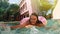 Woman with sunglasses in blue bikini lying in inflatable pink donut float in pool on sunny summer day. Look at camera