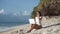 Woman in sunglasses works on beach with laptop, typing text