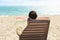 Woman with sunhat relaxing on deck chair at beach resort