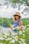 Woman in sunhat and sunglasses picking wildflowers at lake