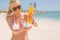 Woman with sunscreen bottle on the beach