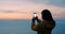 Woman, sunset and phone for photography, ocean and wind with travel influencer hiking for view. Content creation, mobile