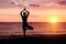 Woman at sunset practicing yoga. Seashore, silhouette