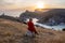 Woman sunset sea mountains. Happy woman siting with her back on the sunset in nature summer posing with mountains on