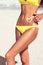 Woman with suntan lotion in form of the heart in yellow bikini.