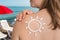 Woman with suntan lotion on her shoulder in sun shape