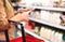 Woman in supermarket aisle with food shelf reading shopping list