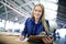 Woman, supervisor and writing with clipboard in logistics at factory with machines for supply chain. Portrait, warehouse