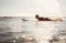 Woman surfer floating on the long surfboard towards line up