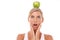 Woman, surprise and apple on head in studio for wellness, nutrition and balance by white background. Isolated model