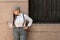 Woman with suspenders looking at pocket watch against wall. Time, precision, waiting, retro concept