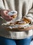 A woman in a sweater holding muffins with icing sugar in her hands. Cozy photo in the style of life. Homemade pastries on wooden