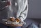 A woman in a sweater holding muffins with icing sugar in her hands. Cozy photo in the style of life. Homemade pastries on wooden