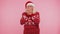 Woman in sweater Santa Christmas hat fooling around having closing eyes with hand and spying through