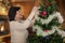 Woman in sweater tinsels Christmas tree