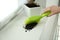 Woman sweeping away scattered soil from window sill with brush