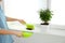 Woman sweeping away scattered soil from window sill with brush