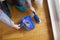 Woman sweeping floor and collecting dust onto a dustpan