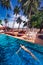 Woman swimming floating in the pool in a tropical seaside resort on the beach. Deck chairs and umbrellas, palm trees and sky. Sea