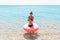 Woman swimming with inflatable donut in cold shivering sad crossed arms black bikini swimsuit standing in sea water. Summer