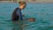 Woman swimming instructor teaches little boy swimming in a sea during a sundet