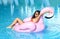 Woman in a swimming pool leisure on a giant inflatable giant pink flamingo float mattress in red bikini