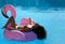 Woman in a swimming pool leisure on a giant inflatable giant pink flamingo float mattress in red bikini