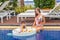 Woman in swimsuit with floating breakfast in swimming pool in luxury hotel