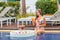 Woman in swimsuit with floating breakfast in swimming pool in luxury hotel