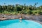 Woman in swimsuit relaxing in infinity swimming pool and watching wide rocky river landscape with jungle banks in Pinnawala