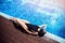 Woman in swimsuit, sunglasses and protective black mask sunbathes against backdrop of hotel pool on sun lounger