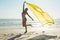 Woman in swimwear waving yellow scarf on the beach