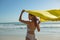 Woman in swimwear waving yellow scarf on the beach
