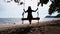 woman swinging on a wooden swing at sunset beach