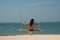 Woman swings enjoying vacation on exotic resort by ocean
