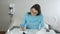 A woman at the table in her apartment takes apart utility bills and envelopes, puts a stamp on the document