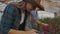 A woman with a tablet examines the flowers and presses her fingers on the tablet screen. Flower farming business