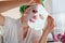 Woman takes off facial sheet mask at home after bath. Healthy skincare routine. Beauty products and cosmetics