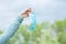 Woman takes off medical protective mask and holds it in hand on green park background. Quarantine is over. Freedom is the new life