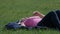 Woman takes off the sunglasses and rests on the grass under the sun