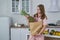 A woman takes out a large pineapple from a paper bag with food. White kitchen with fruits and vegetables