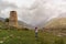 A woman takes a photo of a beautiful landscape on a background of mountains and an ancient watchtower.