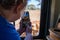 Woman takes a photo of cattle crossing the road in front of the vehicle, through the car window