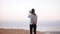 Woman takes photos of montain scenery. Slow motion. Casual traveler girl with backpack using smartphone. Israel Dead Sea