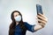 Woman takes selfie photo during illness covid-19 flu virus. girl in headphones and protective mask photograph on phone