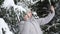 a woman takes a selfie on a smartphone in a snowy forest near a Christmas tree. beautiful snowy winter in the spruce