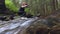 The woman takes water into a mug from a stream